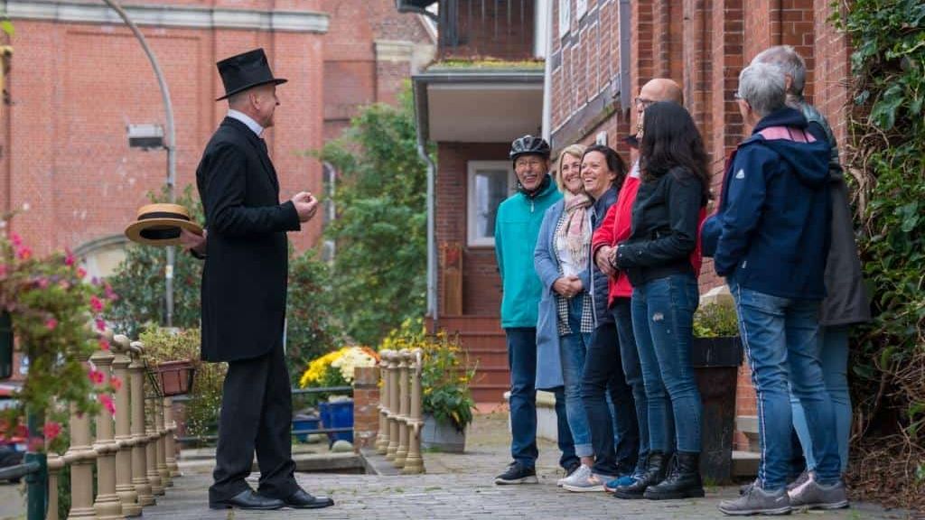 Gruppe von Personen mit dem Ortsführer vor einem historischen Haus 